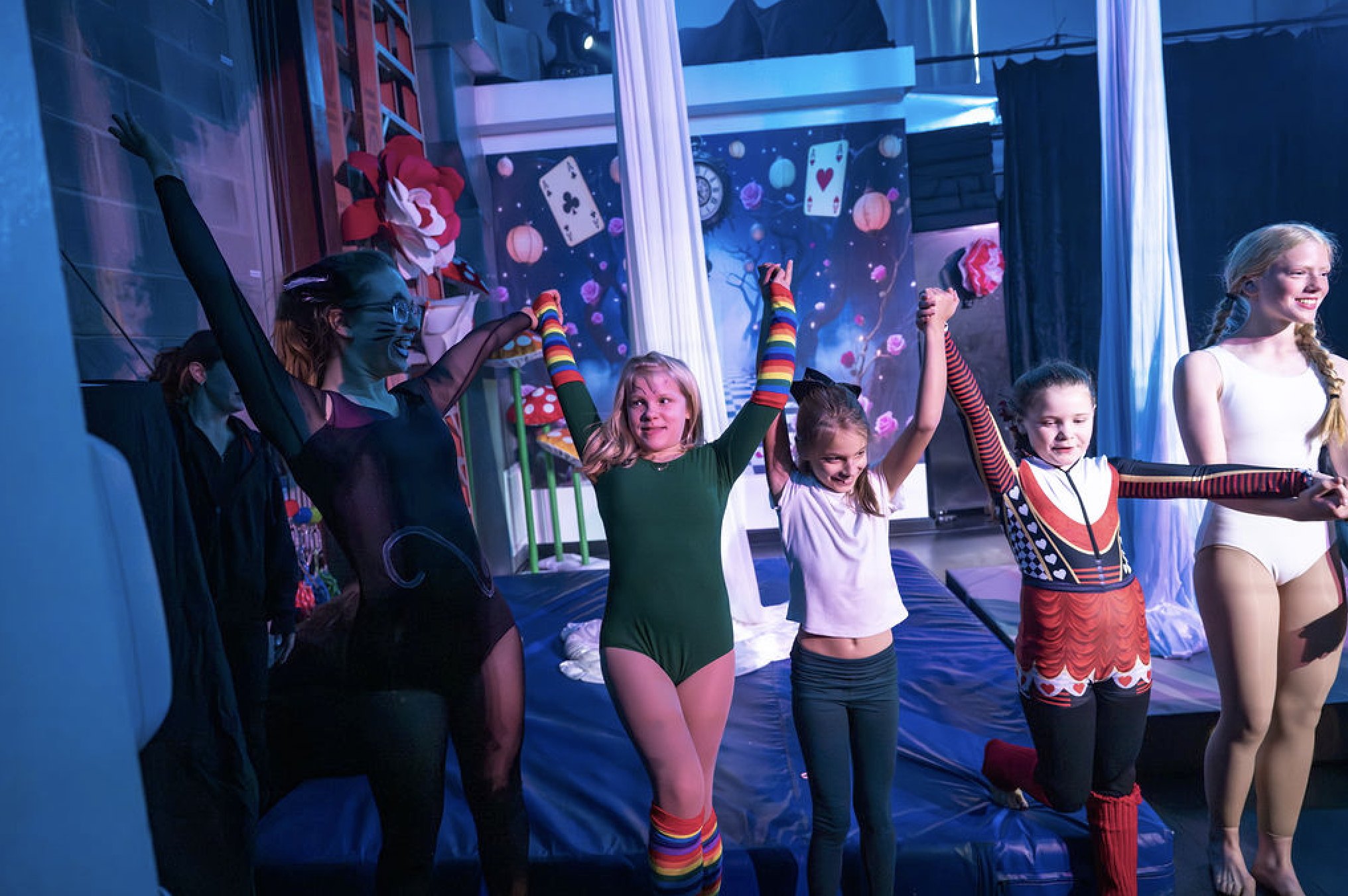 Young aerial students raising their hands together after a performance