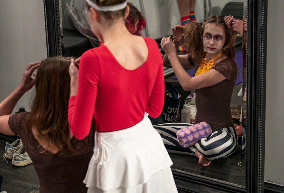 Young performers getting into costume and makeup at the mirror backstage